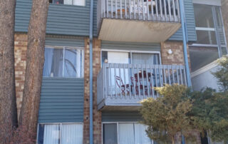 Three-story apartment with brick and blue siding, balconies, leafless trees, and newly restored roofing in Colorado Springs.