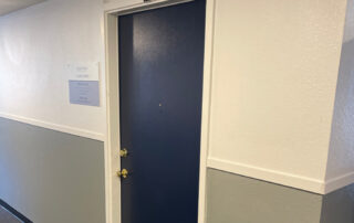 A blue door labeled 114 with two gold locks, ideal for Colorado Springs exterior home restoration or roofing projects, in a hallway.