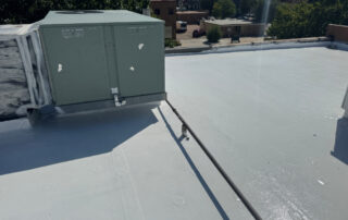 Rooftop with HVAC units and pipes, coated white for energy efficiency during exterior restoration in Colorado Springs; sunny day.
