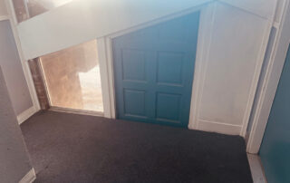 A small blue door under a slanted ceiling, evoking the cozy interiors common after roofing restoration in Colorado Springs homes.